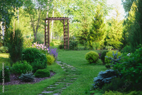 Foto Beautiful summer garden view with curvy stone pathway and wooden archway