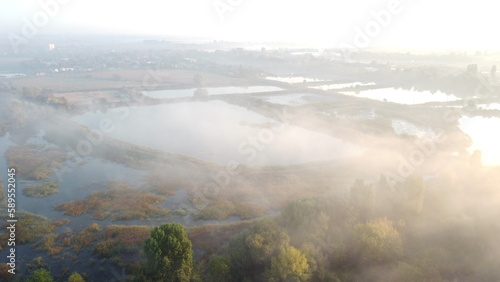 Lakes, artificially created water ponds for growing fish farming with morning mist on an early summer sunny morning. Nature scenery, natural landscape. Sunlight, sunshine. Top view. Aerial drone view. © mari1408