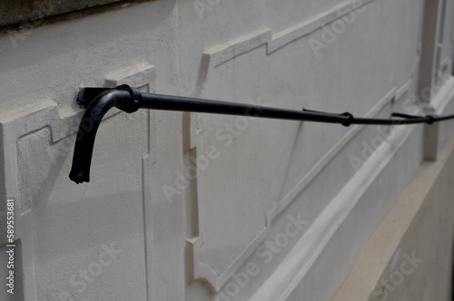 a railing on the wall of a historic building formed by a metal forged rod. plaster of white, red and pink baroque buildings