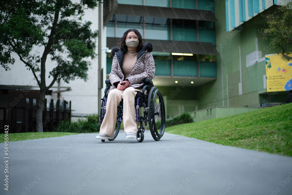 Woman wearing a face mask in wheelchair outdoors Woman wearing a face mask in wheelchair outdoors