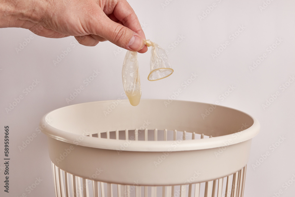 Throw the used condom in the trash. Disposal and recycling of condoms. Stock Photo Adobe Stock