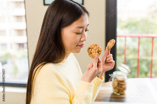 asian pretty woman eating cookies at cool living room
