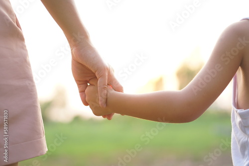 mother and child holding hands in sunset background