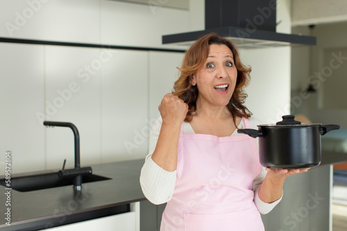 middle age pretty woman feeling shocked,laughing and celebrating success. cooking at home concept