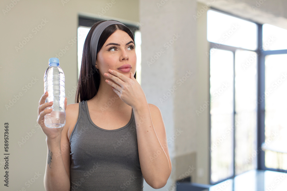 pretty young woman smiling with a happy, confident expression with hand on chin. water bottle concept pretty young woman smiling with a happy, confident expression with hand on chin. water bottle concept