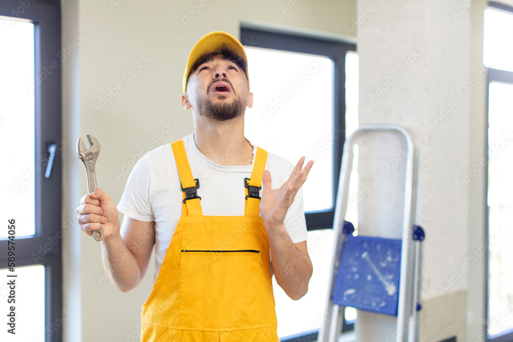 young handsome man screaming with hands up in the air. handyman concept young handsome man screaming with hands up in the air. handyman concept