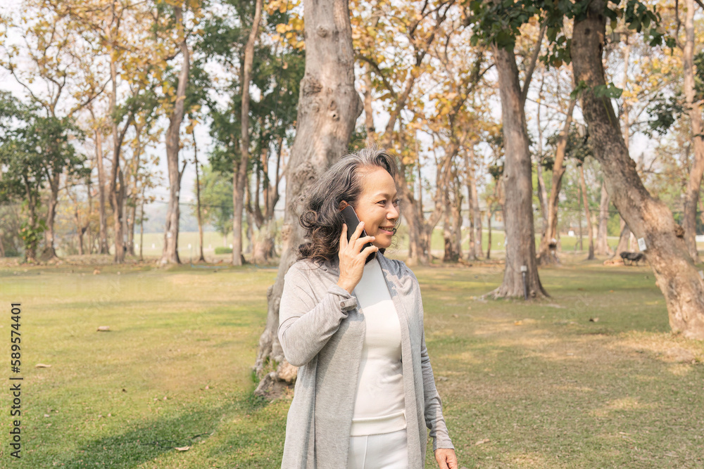 Happy senior woman at park using mobile phone. Cute elderly woman receive a message phone for her beloved Happy senior woman at park using mobile phone. Cute elderly woman receive a message phone for her beloved