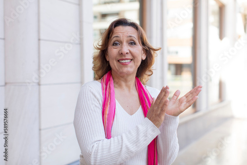 middle age woman feeling happy and successful, smiling and clapping hands, saying congratulations with an applause