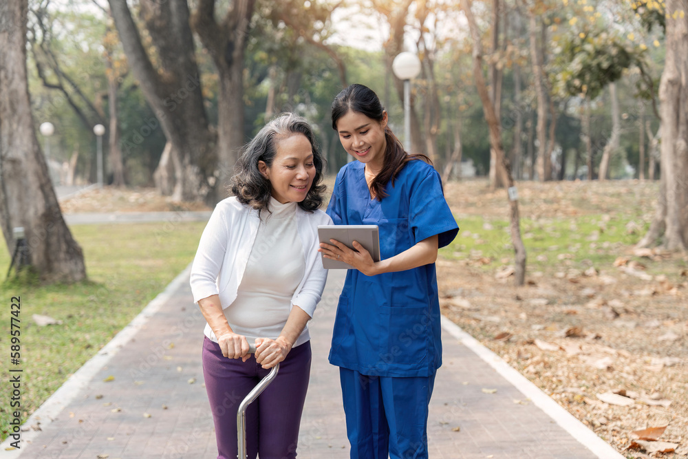 nurse caregiver showing a tablet screen to senior woman and laughing at walking in park for healthcare or nursing home nurse caregiver showing a tablet screen to senior woman and laughing at walking in park for healthcare or nursing home