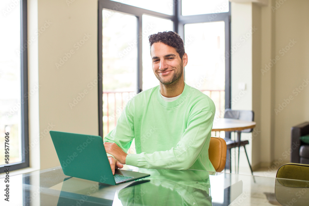 young hispanic man smiling to camera with crossed arms and a happy, confident, satisfied expression, lateral view. working at home