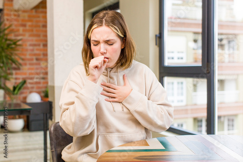 Fotografie pretty caucasian woman feeling ill with a sore throat and flu symptoms, coughing with mouth covered