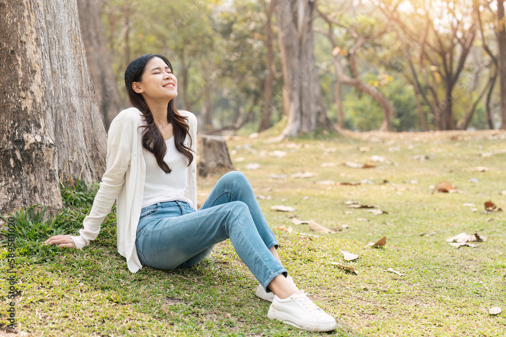 happy Asian woman sitting on grass in the green park, relaxing with nature in the park happy Asian woman sitting on grass in the green park, relaxing with nature in the park