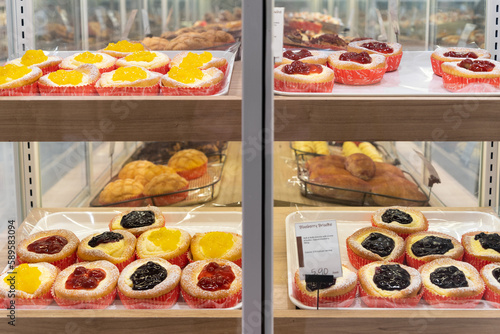 Assorted various types of brioches arranged on tray selling at bakery shop.
