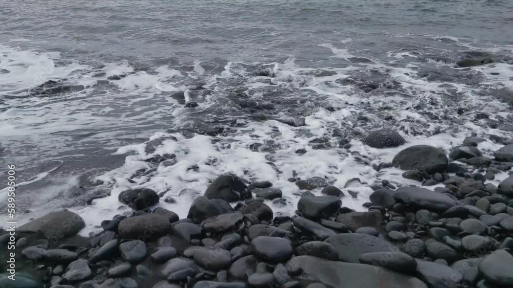 Volcanic beach. Dark water and foam on the beach Volcanic beach. Dark water and foam on the beach