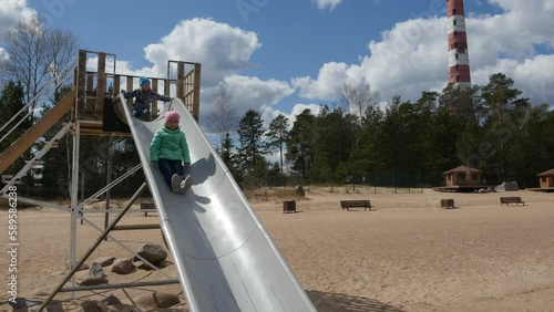 Funny children ride a slide on the playground. Children having fun on a recreation ground. photo