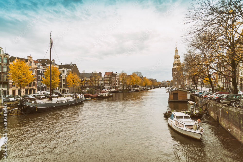 Fototapeta premium Kalkmarkt with the Montelbaanstoren with a canal at the historic old city of Amsterdam with blue sky, the Netherlands
