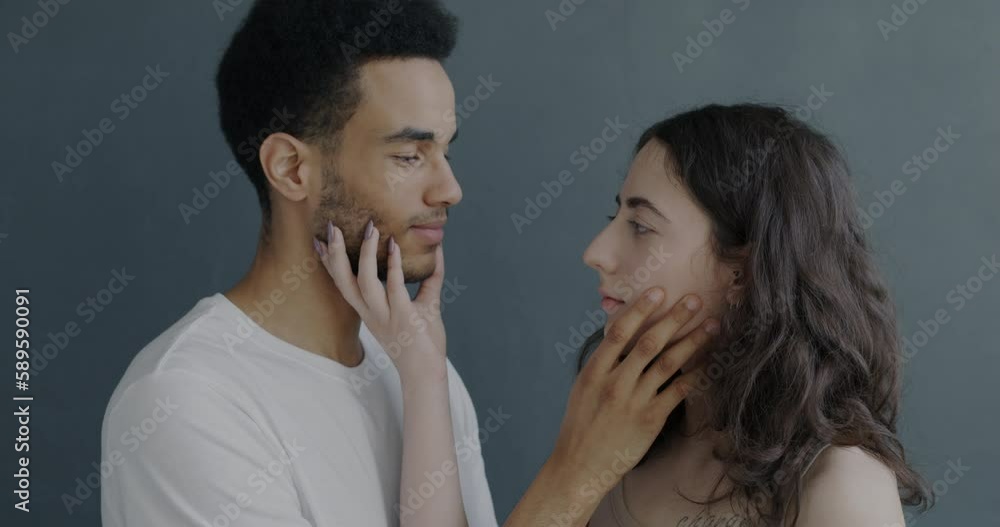 Close-up of biracial couple looking at each other then turning away against gray background. Relationship and personality concept. Close-up of biracial couple looking at each other then turning away against gray background. Relationship and personality concept.