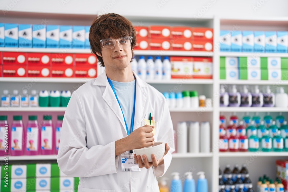 Young blond man pharmacist smiling confident make mixture at pharmacy