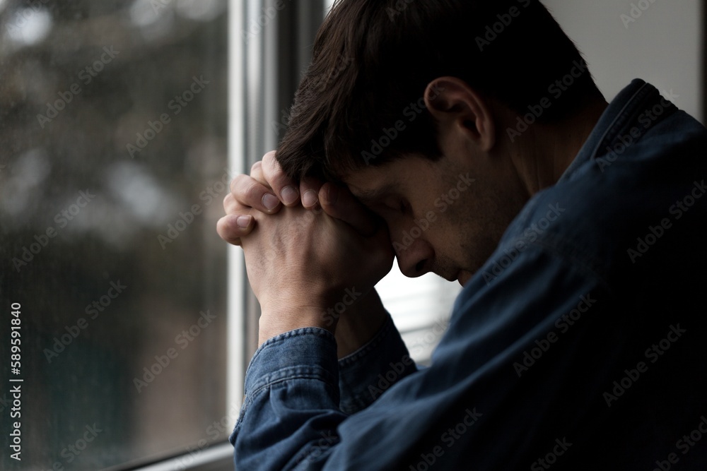 Young mam praying from window. religion concept. Young mam praying from window. religion concept.