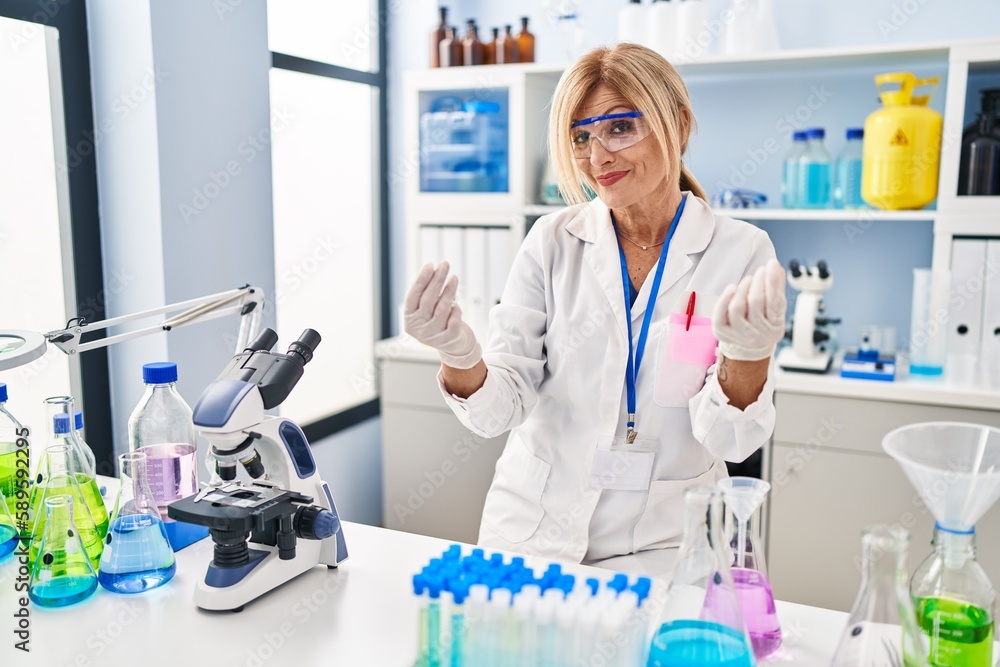 Middle age blonde woman working at scientist laboratory doing money gesture with hands, asking for salary payment, millionaire business Middle age blonde woman working at scientist laboratory doing money gesture with hands, asking for salary payment, millionaire business