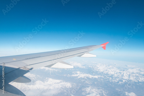 Wing of a low-cost aircraft at high altitude with a view of blue sky and clouds