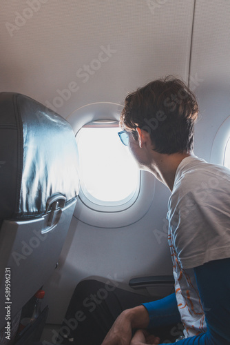 Teenager enjoys travelling on a low-cost plane, fulfilling his adventurous dreams and living his life. A man looks out of the plane's window at the countries he flies over
