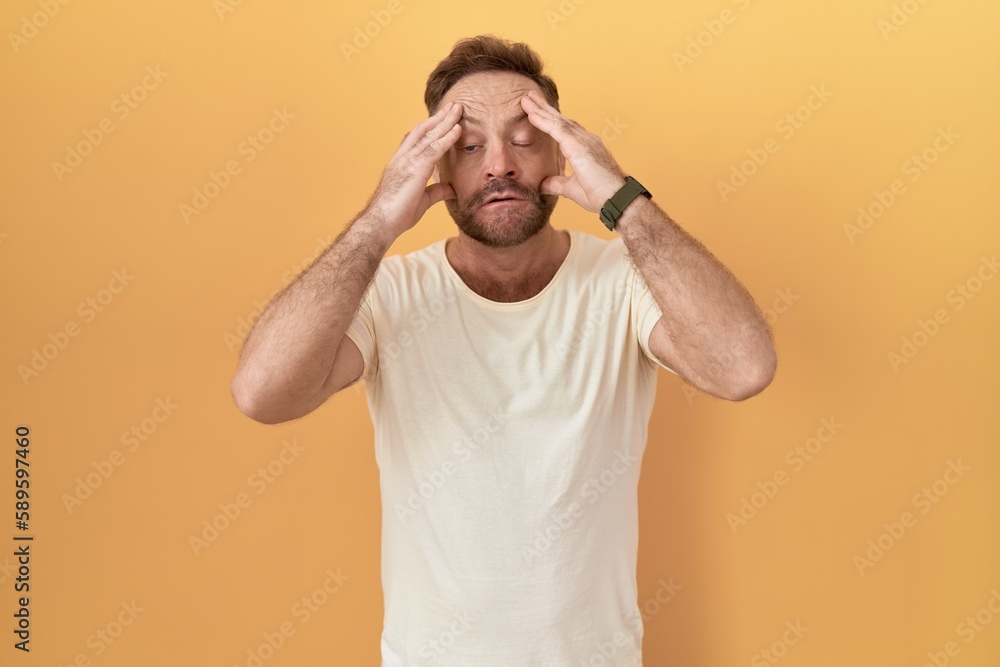 Middle age man with beard standing over yellow background trying to open eyes with fingers, sleepy and tired for morning fatigue Middle age man with beard standing over yellow background trying to open eyes with fingers, sleepy and tired for morning fatigue