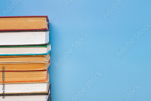 Stack of books in the colored cover lay on blue backround. Education learning concept