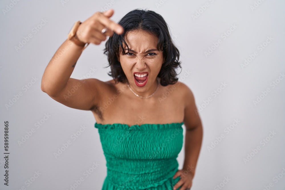 Young hispanic woman standing over isolated background pointing displeased and frustrated to the camera, angry and furious with you