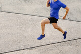 slim muscular male runner running concrete road, top view jogging man in training