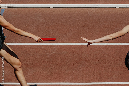 hand female runner passing baton running relay race in summer athletics competition