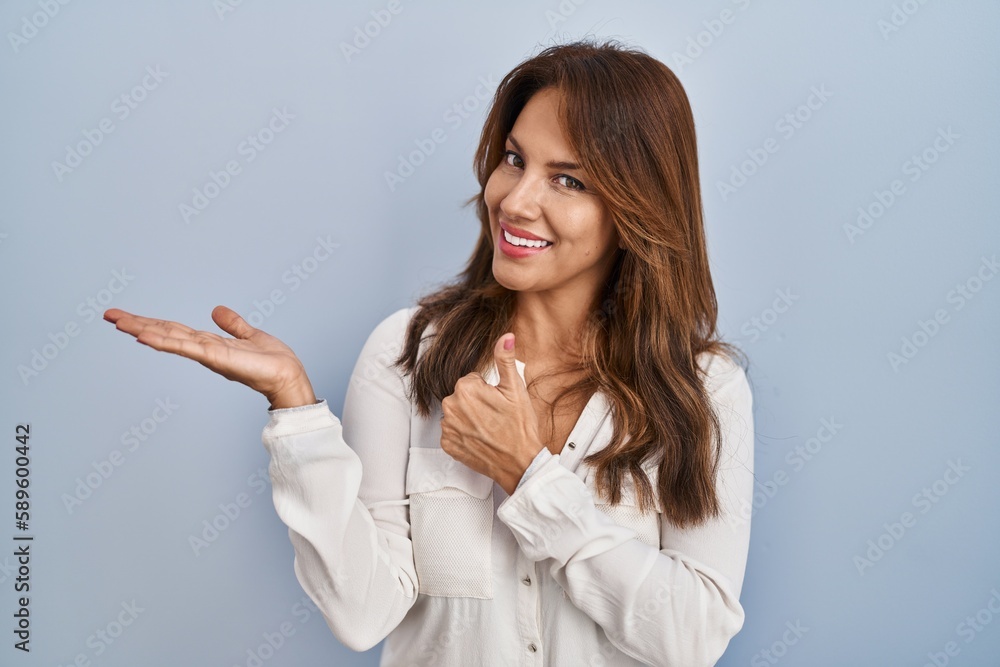 Hispanic woman standing over isolated background showing palm hand and doing ok gesture with thumbs up, smiling happy and cheerful Hispanic woman standing over isolated background showing palm hand and doing ok gesture with thumbs up, smiling happy and cheerful
