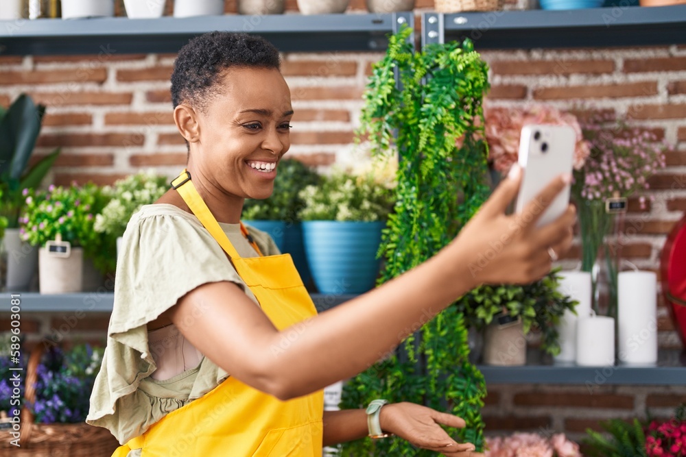 African american woman florist make selfie by smartphone holding plant at florist African american woman florist make selfie by smartphone holding plant at florist
