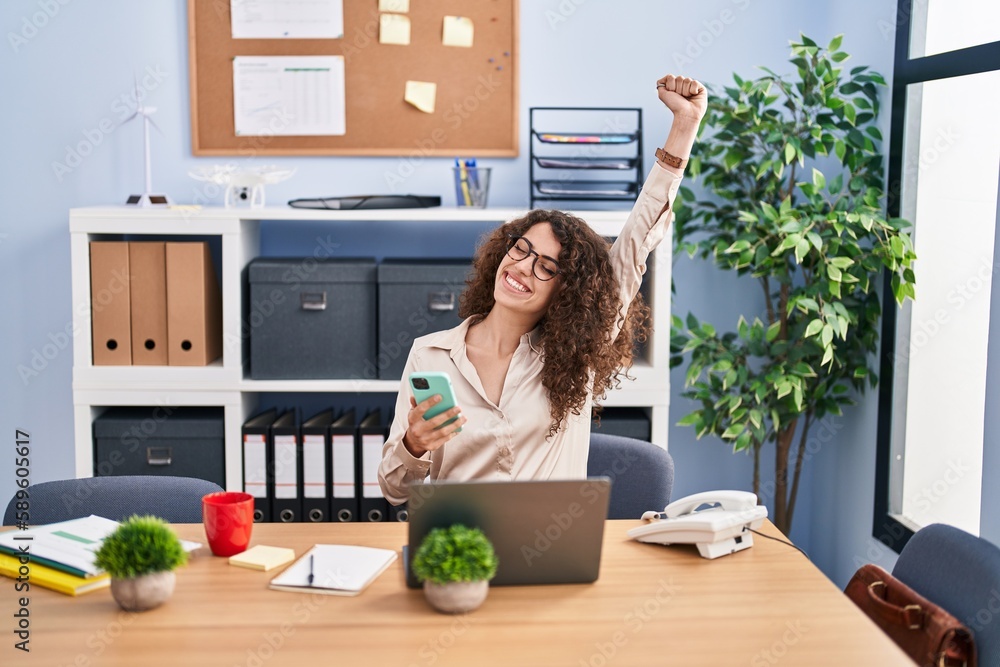 Young hispanic woman business worker using smartphone with winner expression at office Young hispanic woman business worker using smartphone with winner expression at office