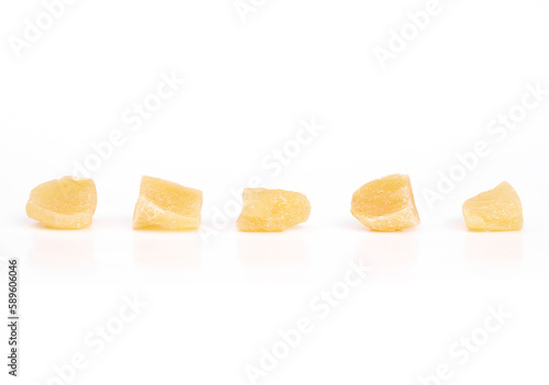 Isolated candied ginger pieces in a row. Yellow chunks of candied or crystallized ginger. Healthy snack for helping with digestive system, motion sickness and immunize system. Selective focus.