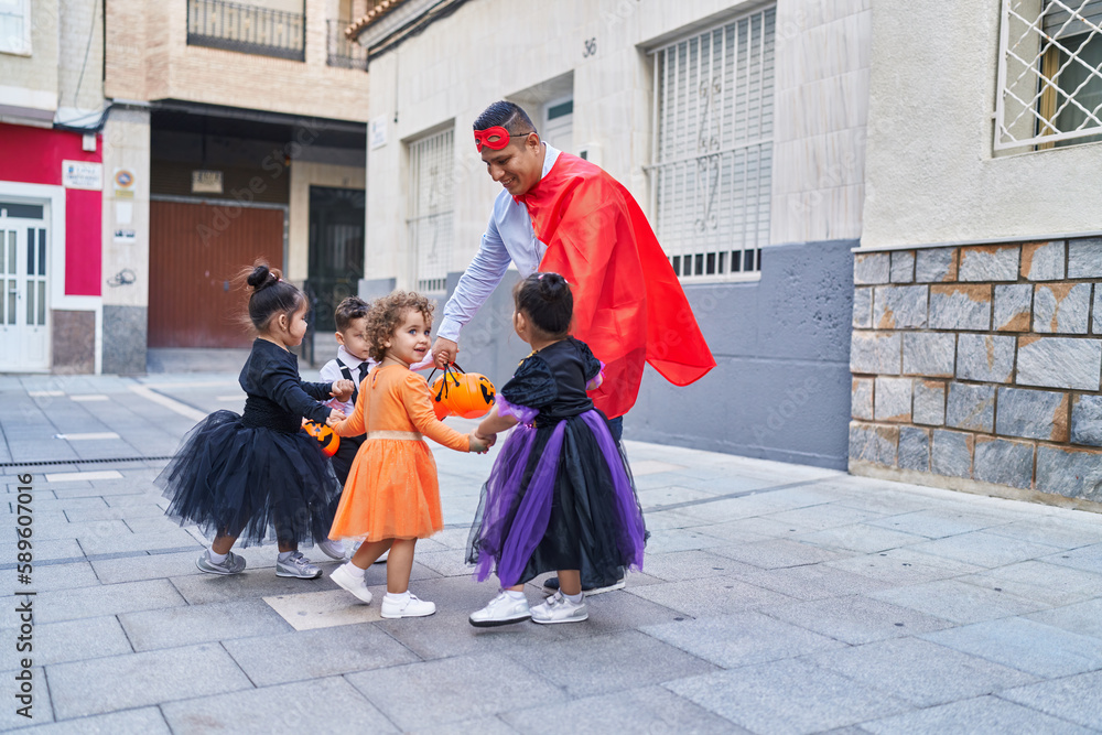 Hispanic man and group of kids wearing halloween costume dancing at street