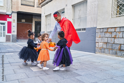 Hispanic man and group of kids wearing halloween costume dancing at street