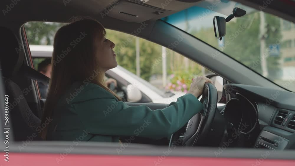 Businesswoman turns steering wheel moving slowly in traffic jam in city center. Young female driver in personal vehicle hurries up to work closeup Businesswoman turns steering wheel moving slowly in traffic jam in city center. Young female driver in personal vehicle hurries up to work closeup
