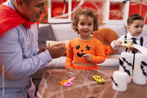 Hispanic man with boy and girl having halloween party at home