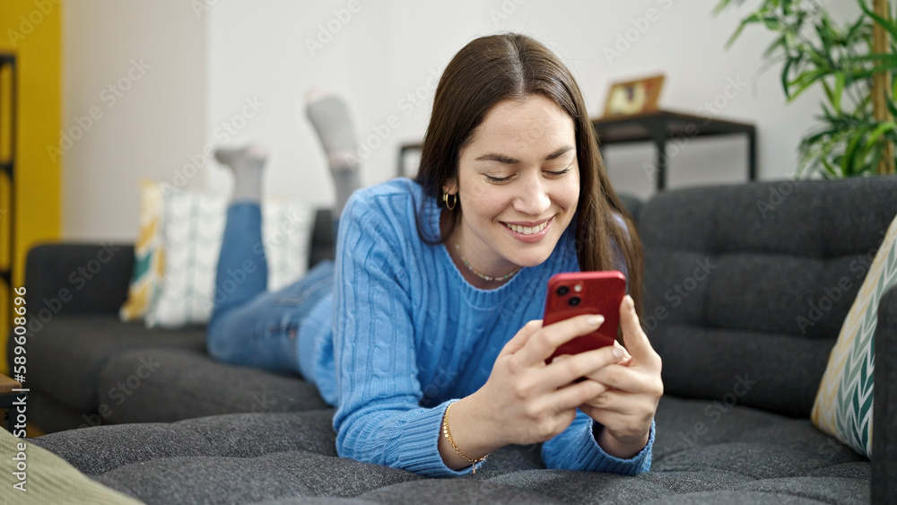 Young caucasian woman using smartphone lying on sofa at home Young caucasian woman using smartphone lying on sofa at home