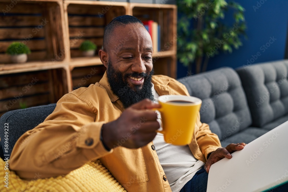 Young african american man reading book and drinking coffee at home Young african american man reading book and drinking coffee at home