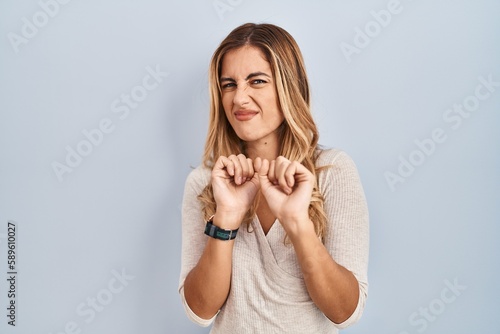 Billede på lærred Young blonde woman standing over isolated background disgusted expression, displeased and fearful doing disgust face because aversion reaction