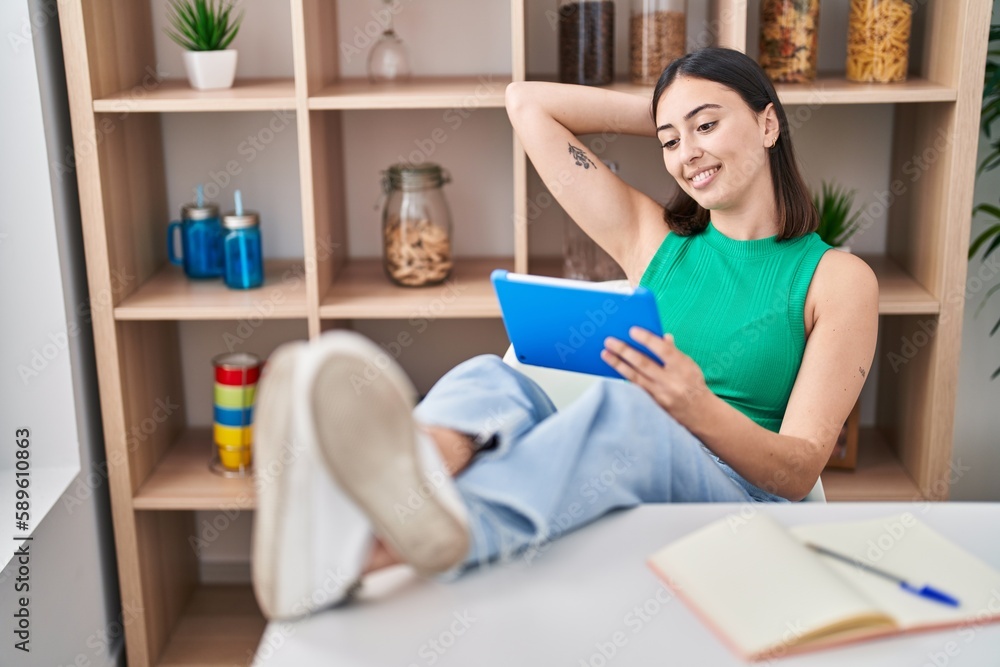 Fototapeta premium Young hispanic woman using touchpad sitting on table at home