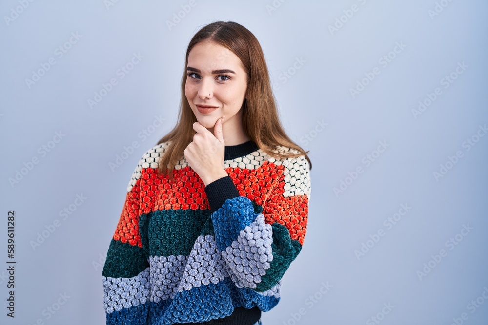 Young hispanic girl standing over blue background looking confident at the camera smiling with crossed arms and hand raised on chin. thinking positive. Young hispanic girl standing over blue background looking confident at the camera smiling with crossed arms and hand raised on chin. thinking positive.