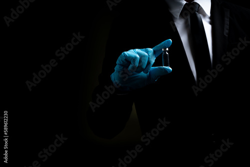 Businessman with black business suit wearing medical protection gloves holding medical  coronavirus vaccine for prevention covid-19 or coronavirus with black background and copy space. Vaccine concept © Thitiwat