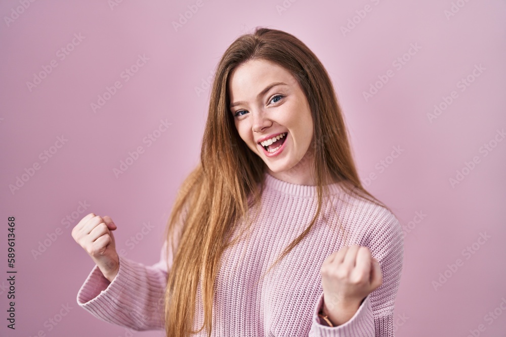 Young caucasian woman standing over pink background very happy and excited doing winner gesture with arms raised, smiling and screaming for success. celebration concept. Young caucasian woman standing over pink background very happy and excited doing winner gesture with arms raised, smiling and screaming for success. celebration concept.