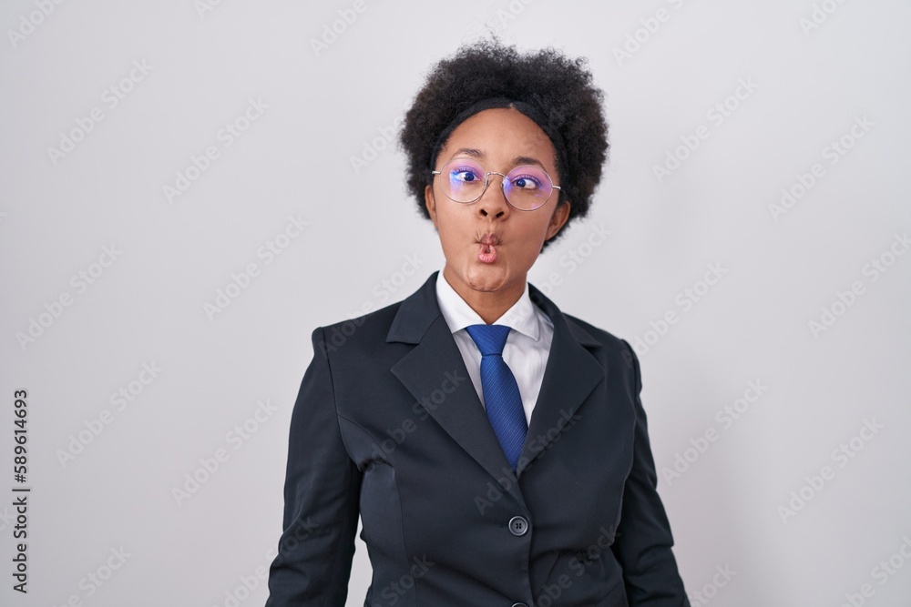 Beautiful african woman with curly hair wearing business jacket and glasses making fish face with lips, crazy and comical gesture. funny expression. Beautiful african woman with curly hair wearing business jacket and glasses making fish face with lips, crazy and comical gesture. funny expression.