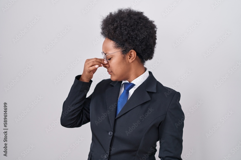 Beautiful african woman with curly hair wearing business jacket and glasses tired rubbing nose and eyes feeling fatigue and headache. stress and frustration concept. Beautiful african woman with curly hair wearing business jacket and glasses tired rubbing nose and eyes feeling fatigue and headache. stress and frustration concept.