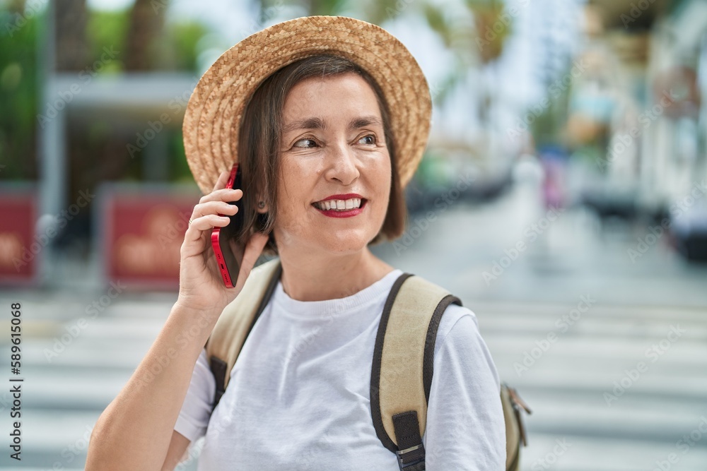 Middle age woman tourist smiling confident talking on smartphone at street