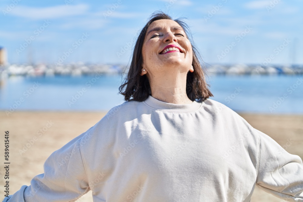 Middle age woman smiling confident breathing at seaside